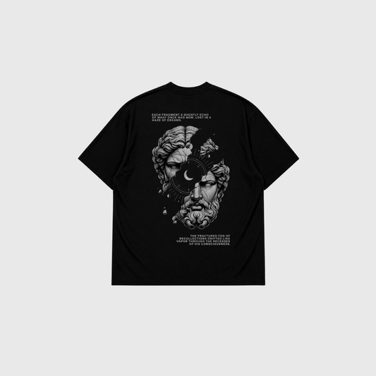 Black oversized T-shirt displayed from the back on a light gray background. Large monochrome graphic of a classical marble statue face split by abstract elements and a crescent moon, with decorative text above and below the artwork.