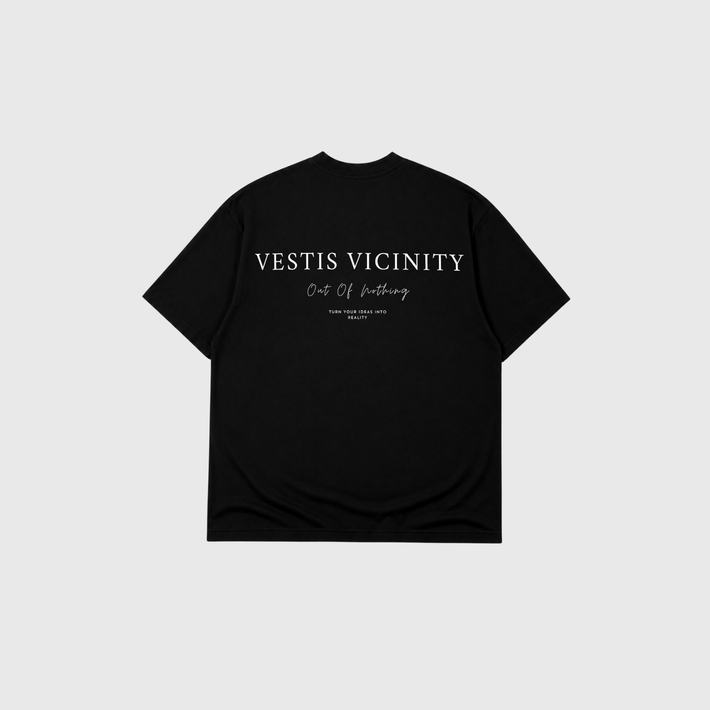 Black oversized T-shirt displayed from the back on a light gray background. Large white typography reading 'Vestis Vicinity' is printed across the upper back, with smaller script and text details underneath.